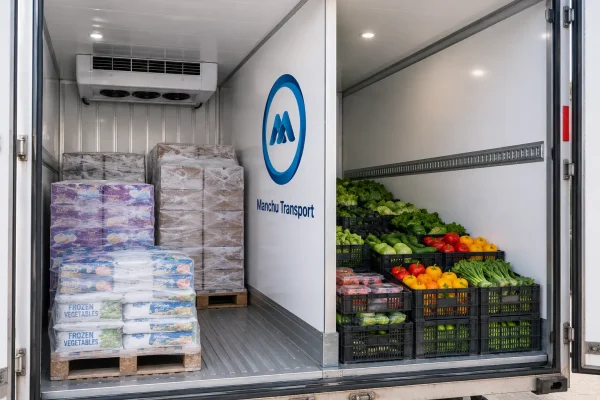 Interior of a dual-zone refrigerated truck showing an insulated bulkhead separating a frozen compartment from a chilled compartment